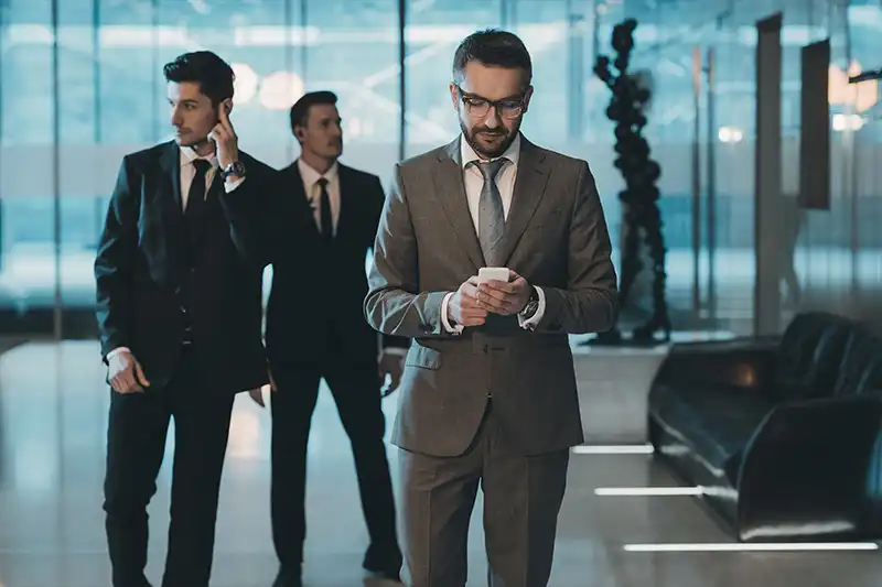 Business professionals in suits, engaged in executive protection training, modern office setting, emphasizing security and risk management.