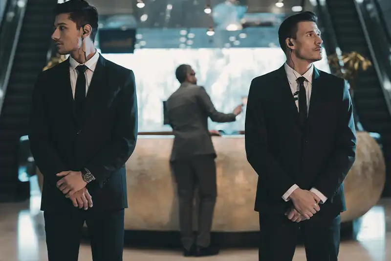Security professionals in suits standing guard at a corporate lobby, emphasizing executive protection and corporate security training.